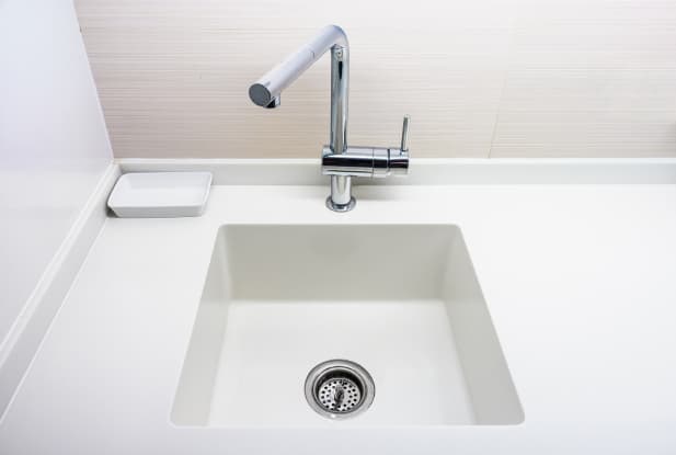 White benchtop with a built in sink cut-out and silver tap and sink hole 