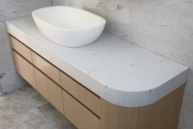 Floating white bathroom basin with a marble benchtop, elevated white sink and wooden draws
