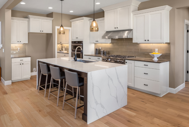 White marble waterfall benchtop on a kitchen island with grey bar chairs and a island sink, all acting as a focal point for the classic white kitchen