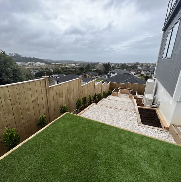 North Shore backyard on a slant with several big steps of pebbles and grass held up by wood retaining walls
