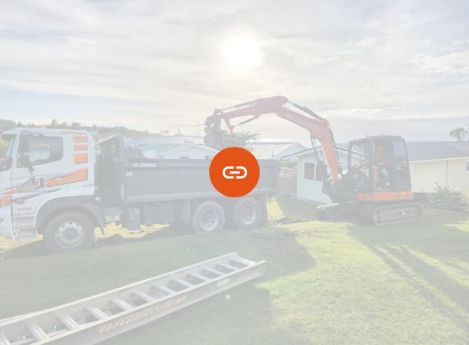 Hired orange earthmoving digger unloading plant debris from a site they're preparing for building foundations
