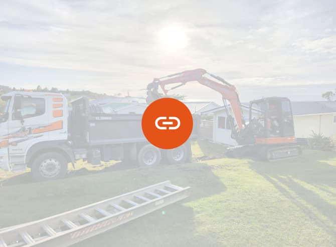 Hired orange earthmoving digger unloading plant debris from a site they're preparing for building foundations