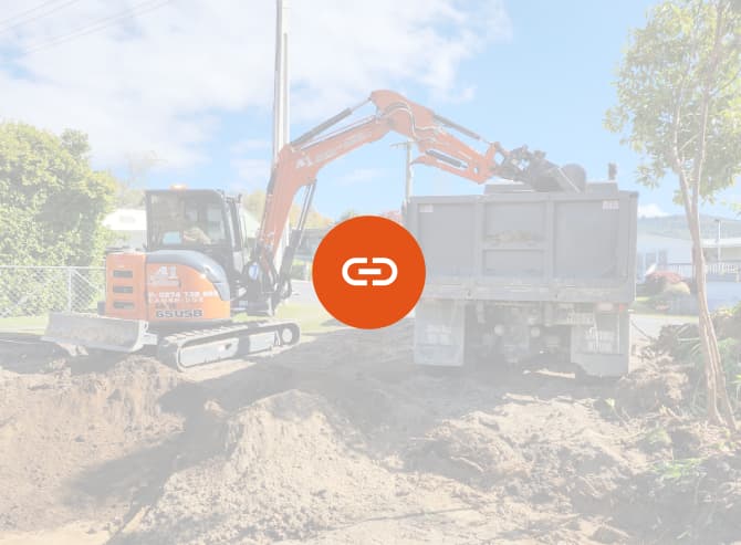 Orange earthmoving digger unloading dirt from a site they're levelling and making ready for building foundations