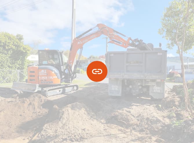 Orange earthmoving digger unloading dirt from a site they're levelling and making ready for building foundations