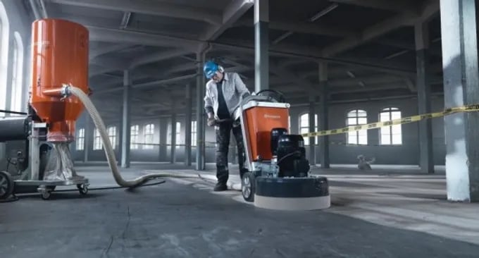 Floorman Waikato staff using a large piece of machinery to polish a concrete floor in a massive  massive commercial building