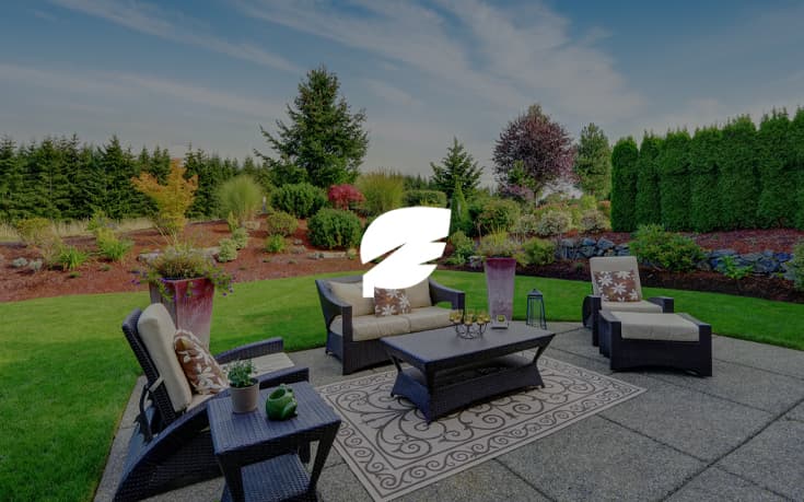 Vibrant and comfortable outdoor sitting area with flowery plants and trees in the distance that surround the whole property