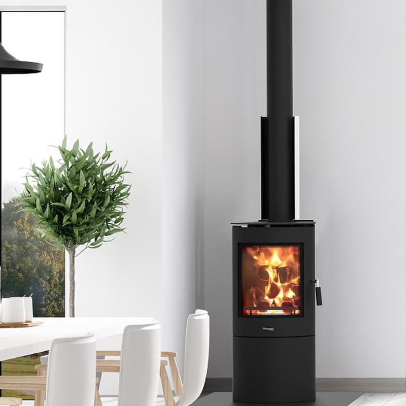 Minimalist white dining area with a tall green plant and slim free standing black fireplace