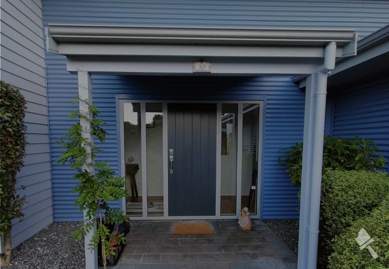 Residential front entrance with weatherboard painted several shades of blue and a navy door