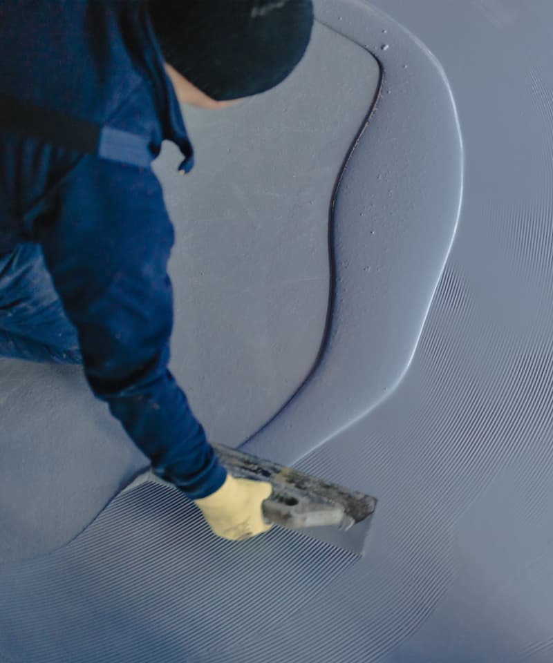Professional painting and decorating team member spreading a grey-blue coating on a commercial floor