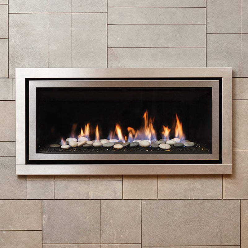 Beige stone tiled wall with an aluminum-framed built-in gas fireplace with stones