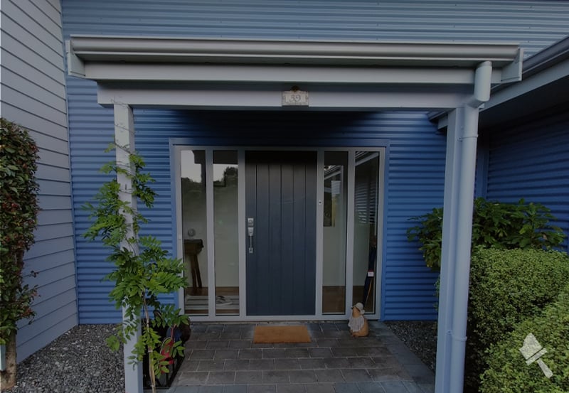 Residential front entrance with weatherboard painted several shades of blue and a navy door