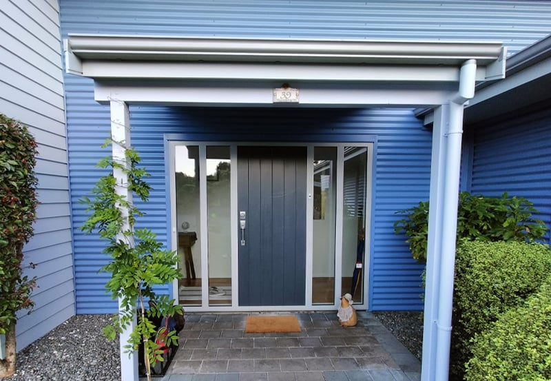 Residential front entrance with weatherboard painted several shades of blue and a navy door