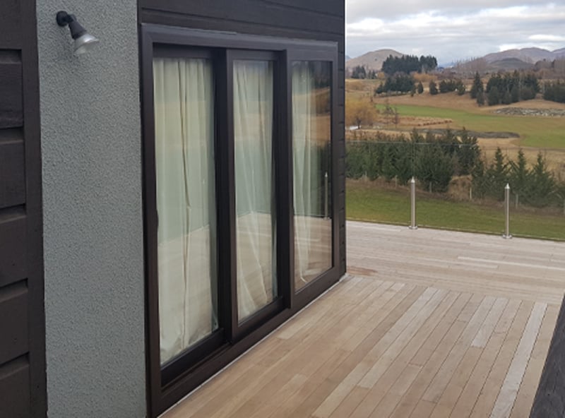 Outdoor deck area on a rural house with a black uPVC sliding door and window frame 