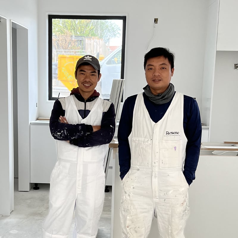 Two of Professional Painting and Decorating's expert painters wearing their Resene white overalls standing in a current site