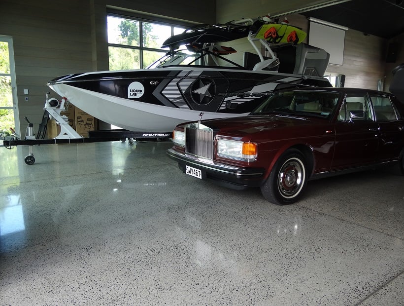Large boat and classic car in a garage with a shiny polished concrete floor by Floorman Waikato