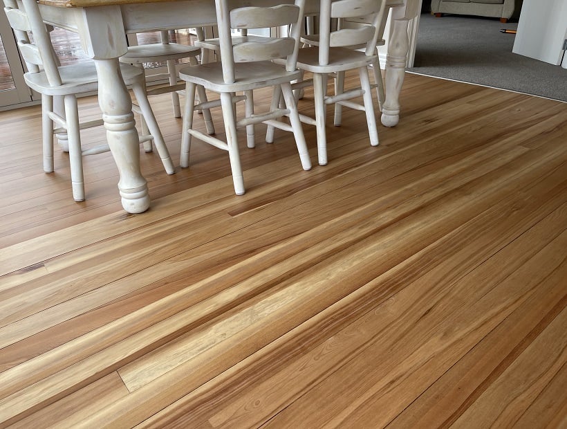 Smoothly sanded and finished timber floor in a residential dining room with a white dining table set 