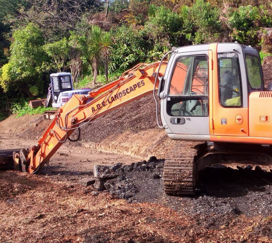 The ABC Excavation and landscaping team with a Vibrant orange digger and a smaller blue digger excavating earth surrounded by nature
