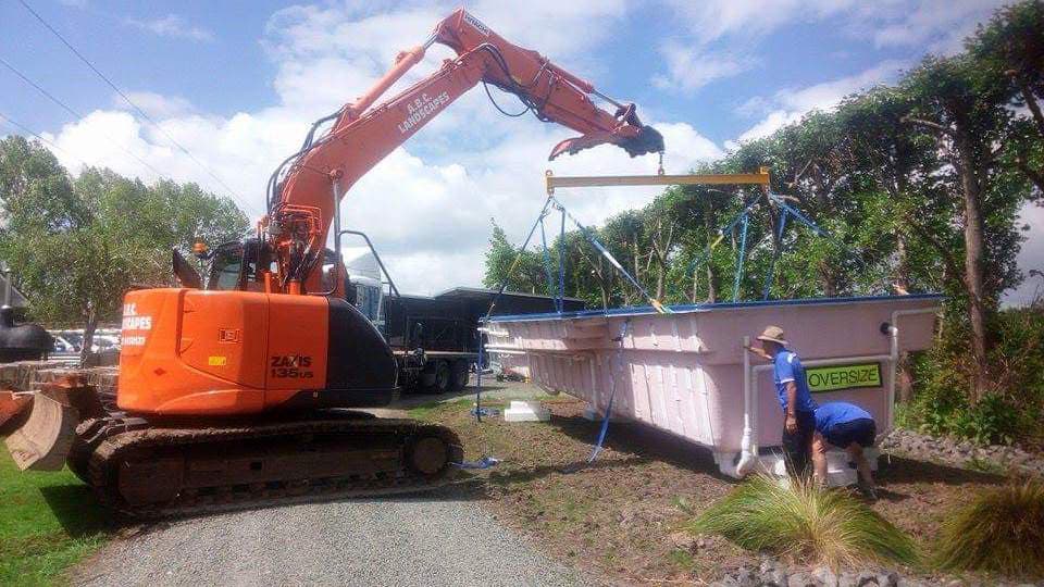 Orange digger lifting a pool off the back of a truck to put in the ground for an Auckland resident